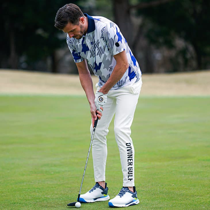 黒いハーフパンツに総柄のポロシャツを着こなし赤いゴルフクラブをもったサングラスの男性